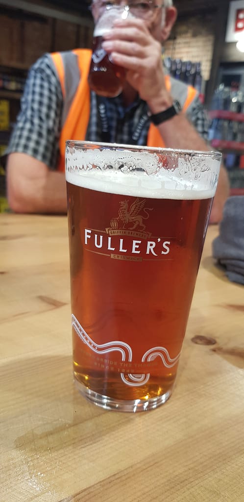 Pint of Fuller's Pride in a Fuller's pint glass with man drinking a pint