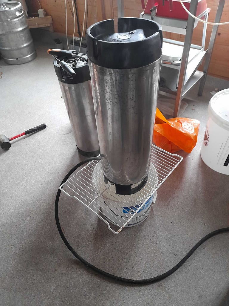 Cornelius keg being steam cleaned on a wire rack and bucket